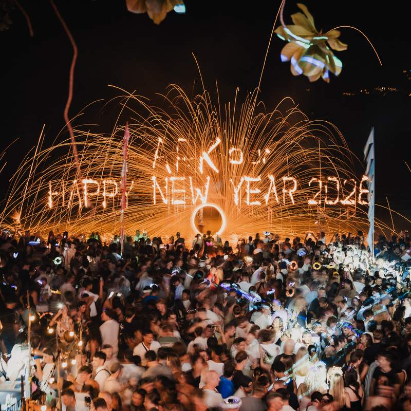 The crowd on the beach facing the burning ARKbar Happy New Year sign