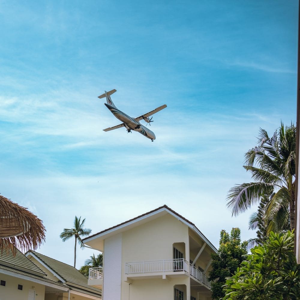 A plane coming in to land low over the ARKbar Beach Resort buildings