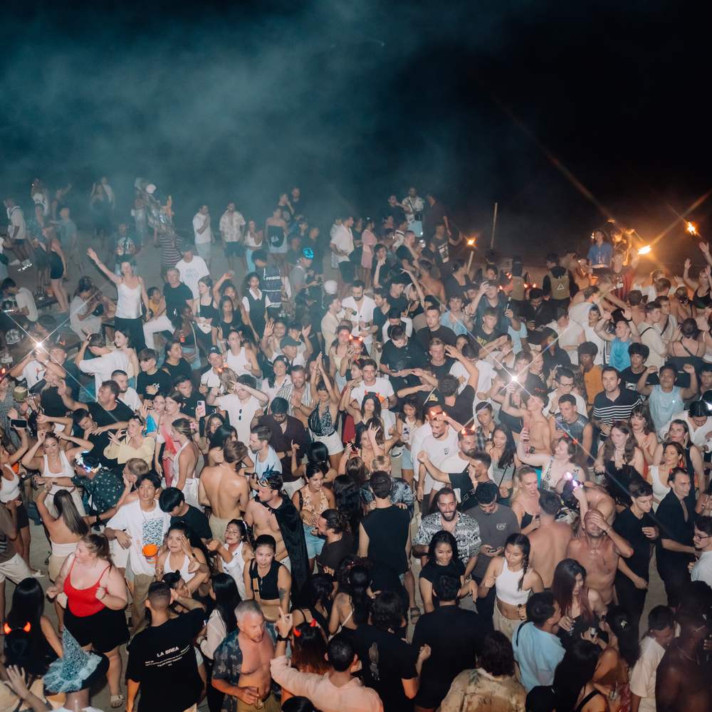 The packed beach at ARKbar on Halloween night 2024, seen from above the crowd